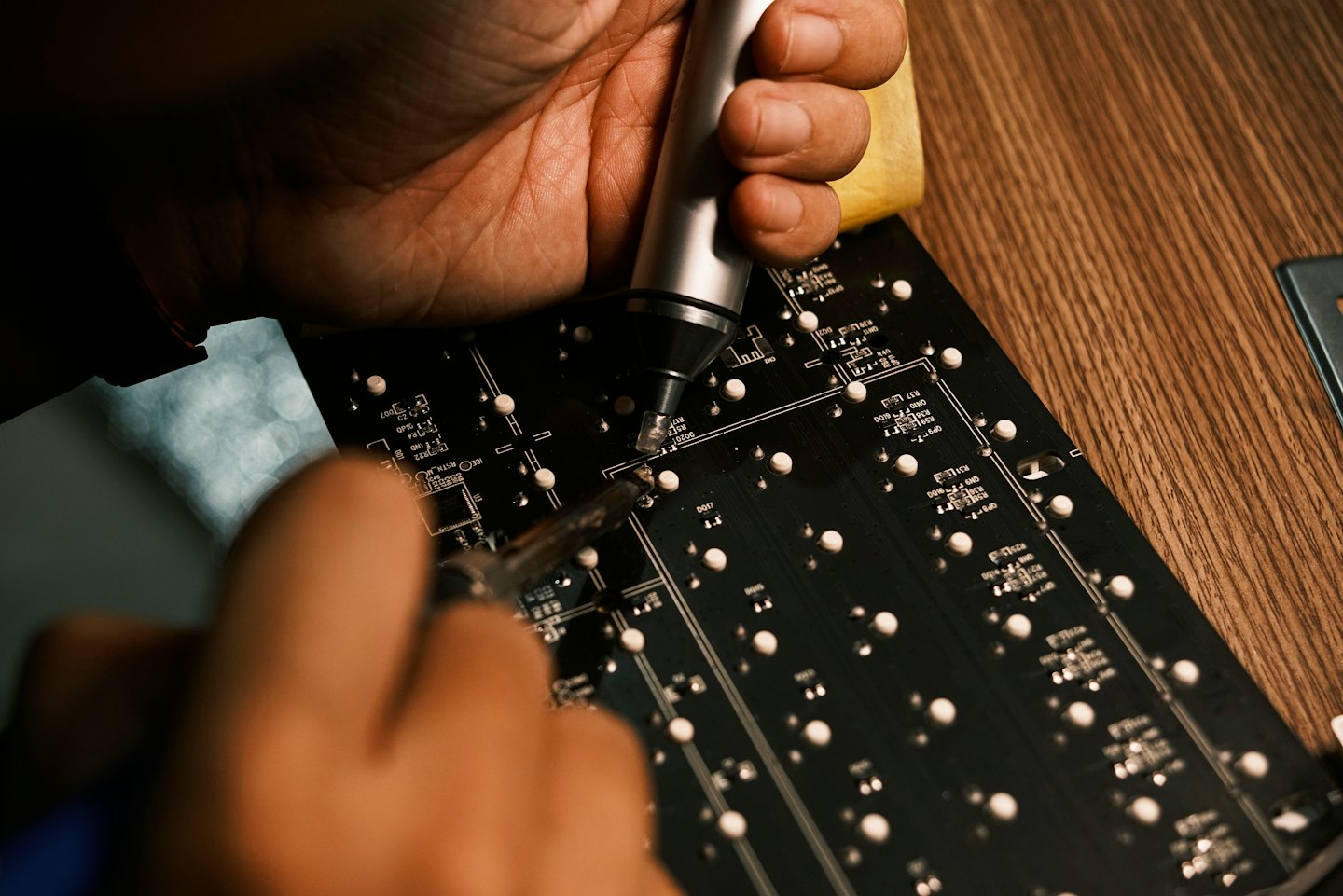 Technician uses soldering tools to repair a circuit board.