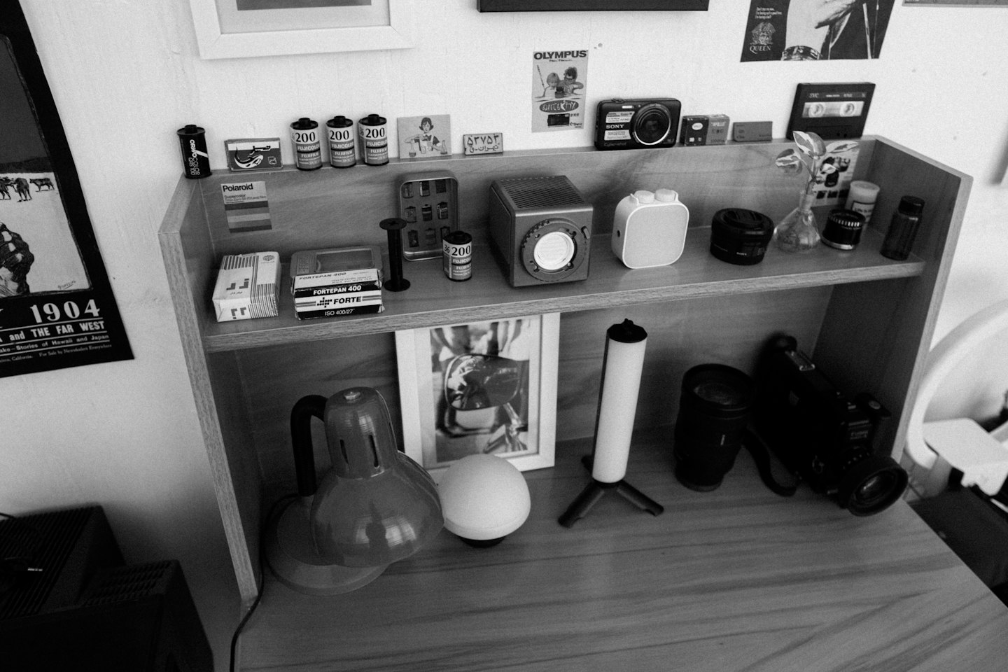 Wooden desk holding cameras and film equipment on tiered shelves.